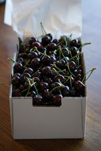 Load image into Gallery viewer, 2 kg box of freshly packed Central Otago cherries from Perriam Orchard on a wooden table, showing glossy dark red fruit with green stems
